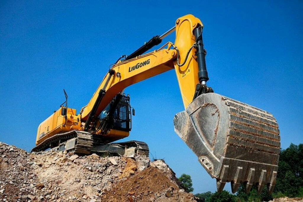 Yellow excavator digging dirt on a sitework and earthwork project against a blue sky